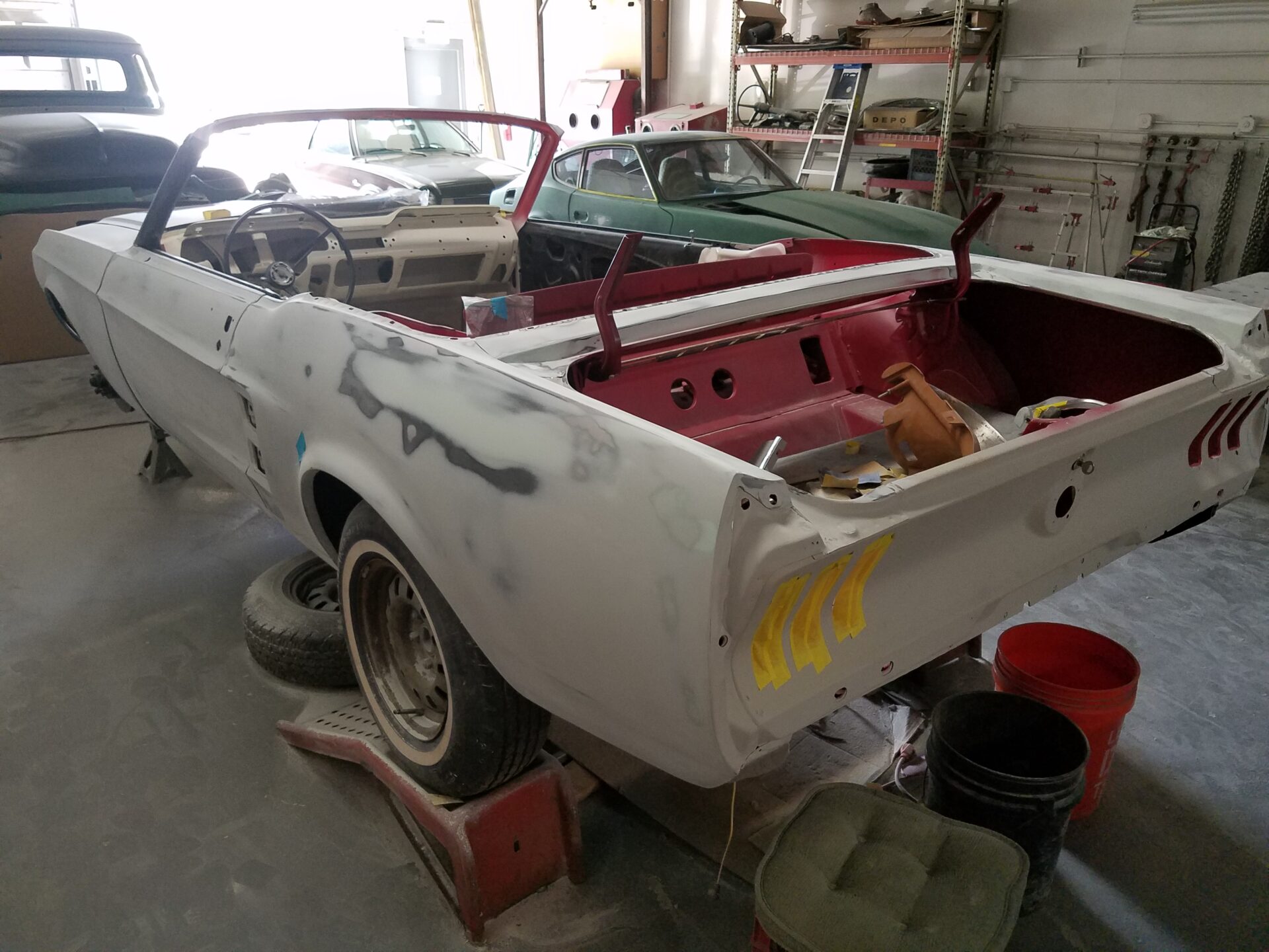 A white 1967 Ford Mustang Convertible undergoing repairs